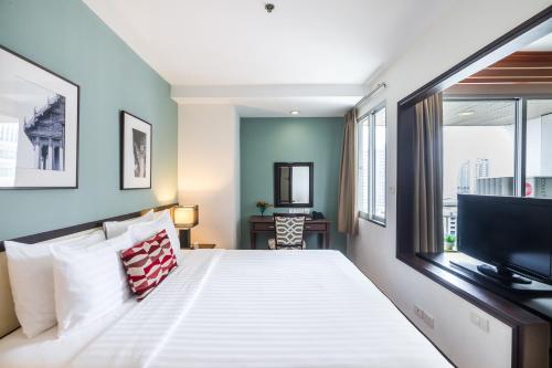 a bedroom with a large bed and a television at Evergreen Place Siam by UHG in Bangkok