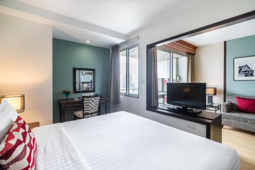 a bedroom with a large bed and a tv at Evergreen Place Siam by UHG in Bangkok