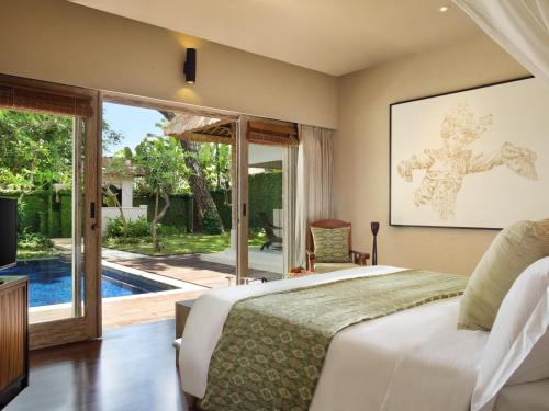 a bedroom with a bed and a tv and a pool at Kayumanis Sanur Private Villa and Spa in Sanur