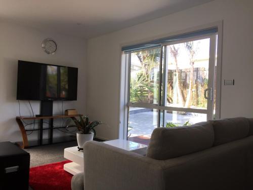 a living room with a couch and a large window at Amber Homes in Auckland