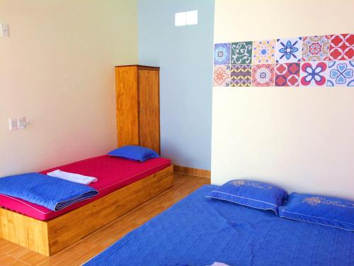 a bedroom with two beds with blue sheets at Bot Bien Homestay in Mui Ne