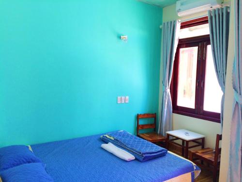 a blue bedroom with a bed and a window at Bot Bien Homestay in Mui Ne