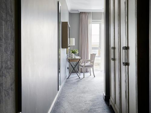 a hallway with a table and a chair in a room at Queen Victoria Hotel by NEWMARK in Cape Town