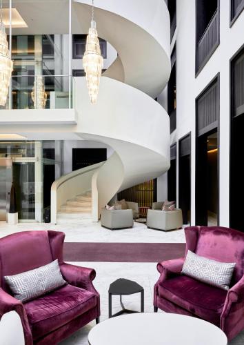 a lobby with purple chairs and a spiral staircase at Queen Victoria Hotel by NEWMARK in Cape Town