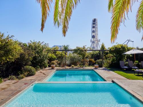 una piscina en un patio con una palmera en The Manor House at the Queen Victoria Hotel by NEWMARK, en Ciudad del Cabo