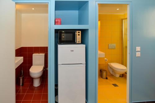 a bathroom with a toilet and a microwave on top of a refrigerator at Athens' heart Syntagma metro apartment in Athens