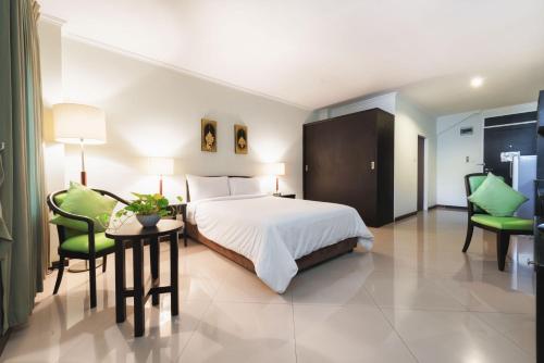 a hotel room with a bed and two green chairs at Capital Mansion - SHA Certified in Bangkok