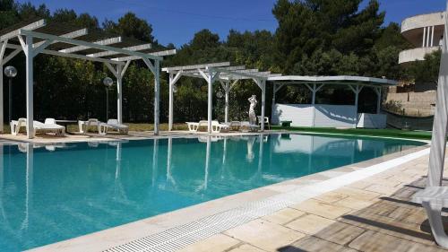 a swimming pool with a pavilion and a swimming pool at Hotel Falco D'oro in Cisternino