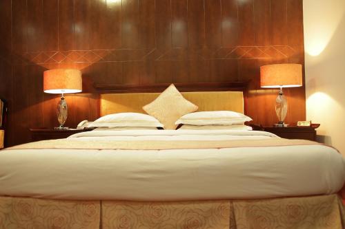 a bedroom with a large bed with two lamps at Kabul Star Hotel & Restaurant in Shīrpūr