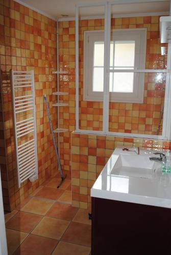 een oranje betegelde badkamer met een wastafel en een raam bij gîte la belle vue in Saint-Martin-en-Campagne