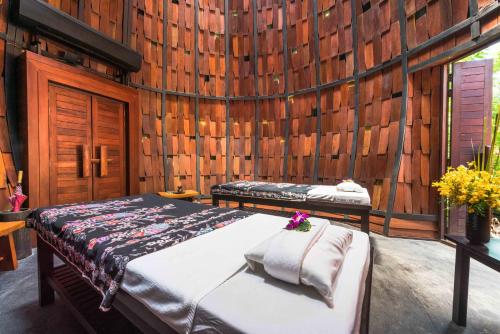 a bedroom with two beds in a wooden wall at The Tubkaak Krabi Boutique Resort - SHA Extra Plus in Tab Kaek Beach