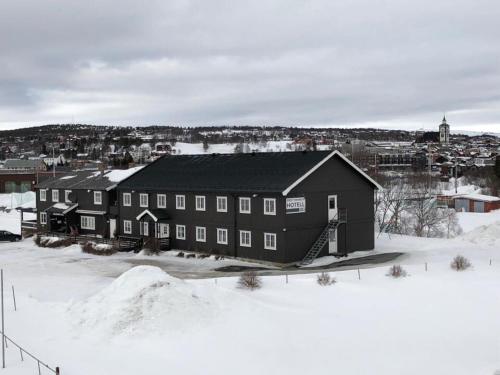 duży czarny budynek z śniegiem na ziemi w obiekcie Rørosvidda Hotell w mieście Røros