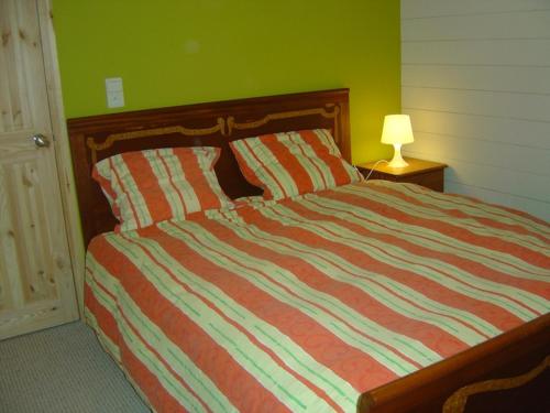 a bed with a striped comforter in a bedroom at La Brindille in Durbuy
