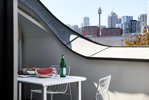 a table with a drink and a bowl of watermelon on a balcony at Veriu Broadway in Sydney
