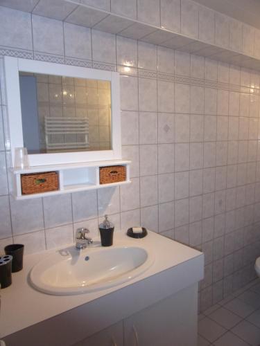 ein Bad mit einem Waschbecken und einem Spiegel in der Unterkunft Maison d'hôtes Fortin Anita et Guy in Pouzauges