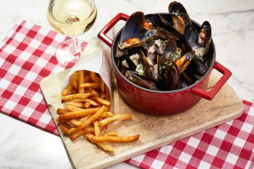 a bowl of mussels and a plate of fries and a glass of wine at Mama Shelter Bordeaux Centre in Bordeaux