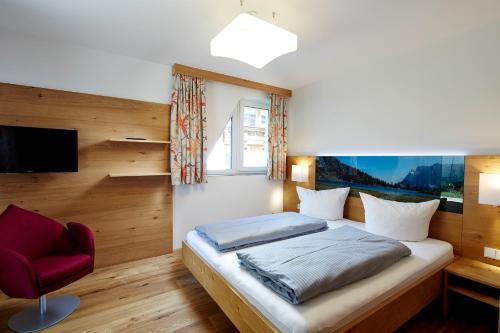 ein Schlafzimmer mit einem Bett und einem roten Stuhl in der Unterkunft Apartment S in Ehrwald