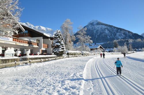 a person is walking down a snow covered street at Hotel Cafe Fuggerhof in Oberstdorf