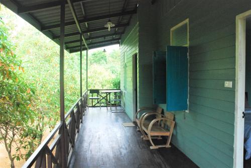 a porch of a green house with a table and chairs at Baantantara in Suan Phung