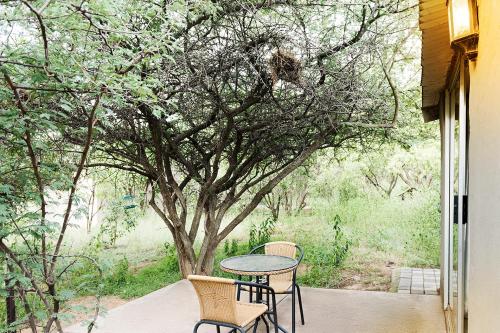 a table and chairs on a porch with a tree at Glenda's Guest Suites in Midrand