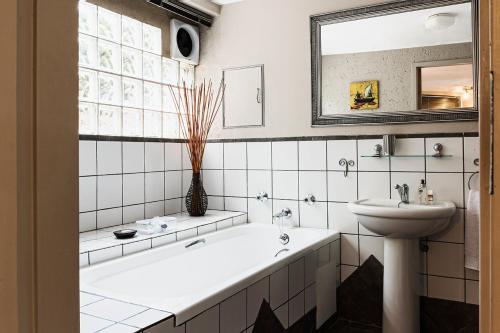 a white bathroom with a tub and a sink at Glenda's Guest Suites in Midrand