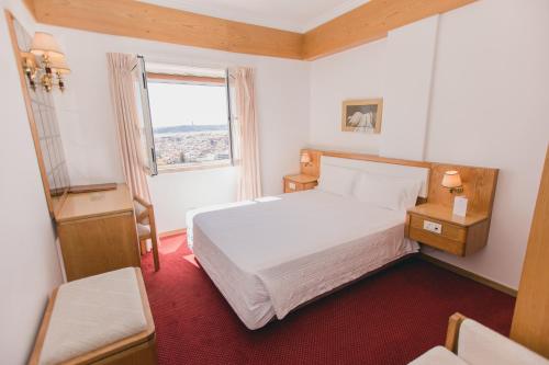 ein Schlafzimmer mit einem weißen Bett und einem Fenster in der Unterkunft Albergaria Senhora do Monte in Lissabon