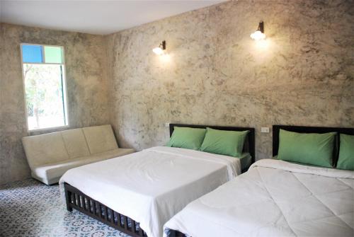 a room with two beds and a couch in it at Baantantara in Suan Phung