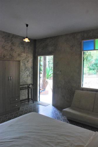 a bedroom with a bed and a couch and a window at Baantantara in Suan Phung