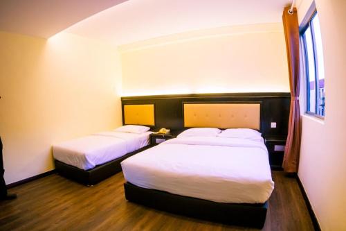 a hotel room with two beds and two lamps at Hotel Zuhra in Sibu