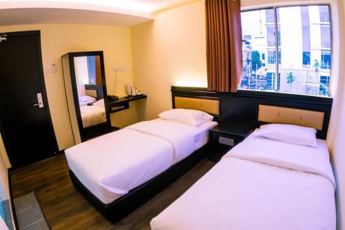 a hotel room with two beds and a mirror at Hotel Zuhra in Sibu