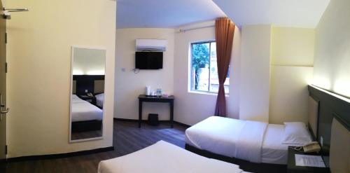 a hotel room with two beds and a mirror at Hotel Zuhra in Sibu