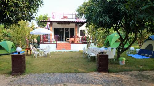 a yard with chairs and tables and a house at Baantantara in Suan Phung