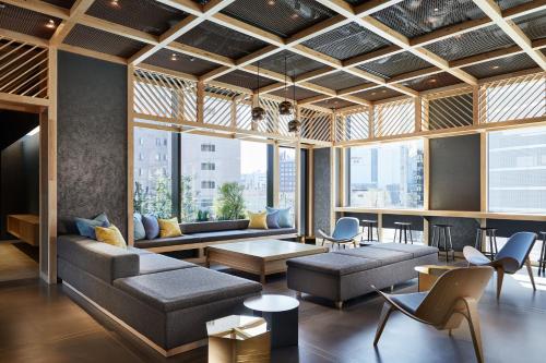 ein Wohnzimmer mit Sofas, Tischen und Fenstern in der Unterkunft OMO5 Tokyo Otsuka by Hoshino Resorts in Tokio