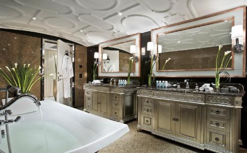 a bathroom with two sinks and a tub and mirrors at The Kunlun Jing An in Shanghai