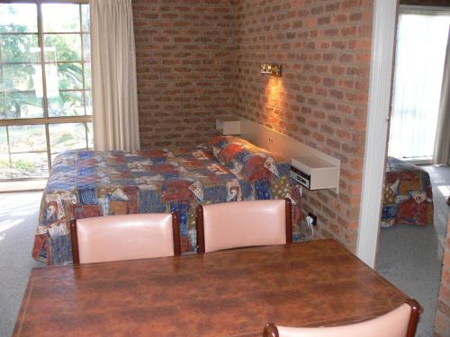 a room with two beds and a table and chairs at Settlement Motor Inn in Deniliquin