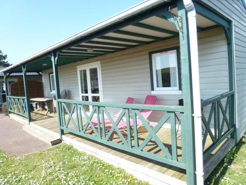 a deck with two pink chairs on a house at Village Vacances Les Sables d'Or in Gouville-sur-Mer