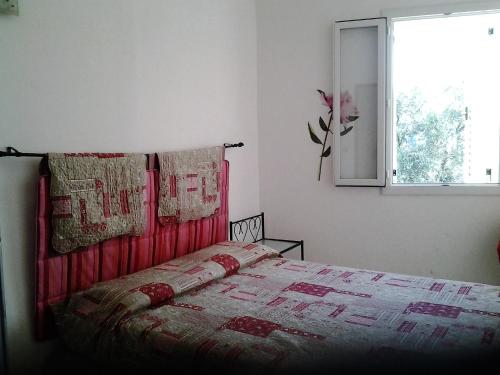 Un dormitorio con una cama con una manta roja y una ventana. en chez marie, en Porto Ota