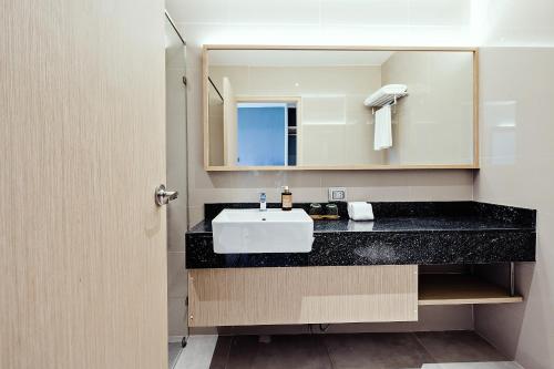 a bathroom with a white sink and a mirror at Three Sukhumvit Hotel - SHA Plus Certified in Bangkok