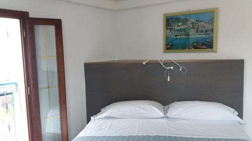 a bed with white pillows and a picture above it at Affittacamere Elisabetta in Vernazza