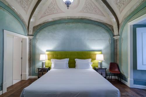 a bedroom with a large bed with a green headboard at Casa Morgado Esporao in Évora
