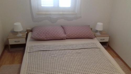 a bed with two pillows on it in a room at Apartman Lovro in Novalja