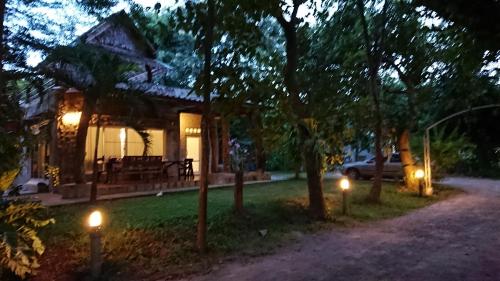 a house with lights in the yard at night at Baantantara in Suan Phung