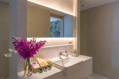 a bathroom with a sink and a mirror and purple flowers at Panan Krabi Resort in Ao Nang Beach
