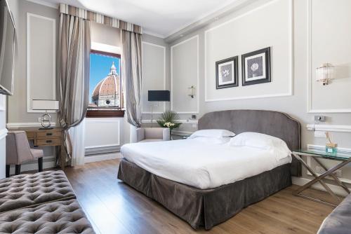 a bedroom with a bed and a desk and a window at FH55 Hotel Calzaiuoli in Florence