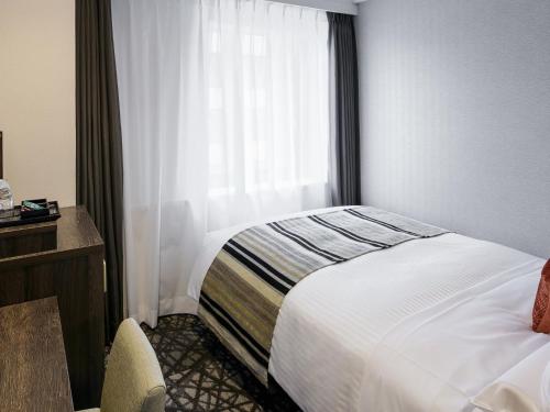 a hotel room with a bed and a window at Hotel Mystays Kagoshima Tenmonkan in Kagoshima