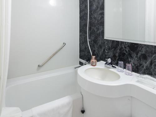 a white bathroom with a sink and a toilet at Hotel Mystays Kagoshima Tenmonkan in Kagoshima