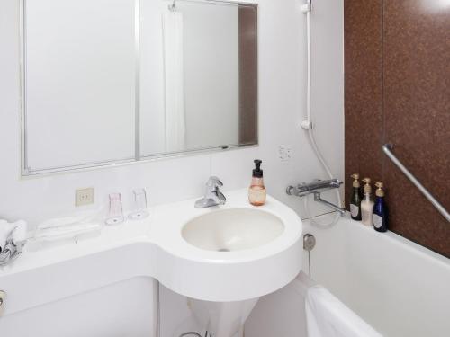 a white bathroom with a sink and a bath tub at Hotel Mystays Kagoshima Tenmonkan in Kagoshima