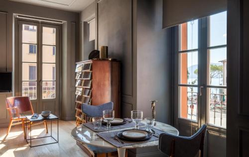 a dining room with a table and chairs and windows at Suites Menaggio in Menaggio