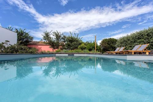 a large swimming pool with chairs and a blue sky at Quinta dos Peixes Falantes in Ribeira Grande