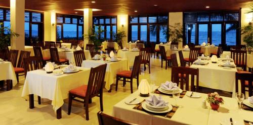 um restaurante com mesas, cadeiras e janelas brancas em Muine Century Beach Resort & Spa em Mui Ne